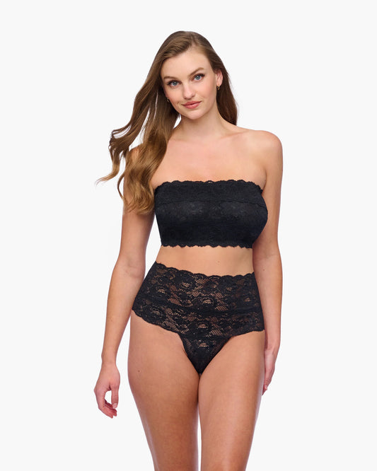 Woman wearing a black lace strapless top and high-waisted underwear on a white background