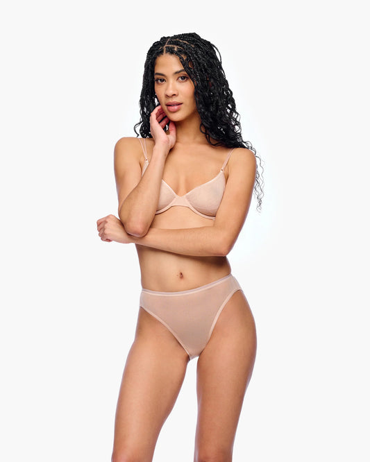 Woman wearing a beige bra and panties set on a white background