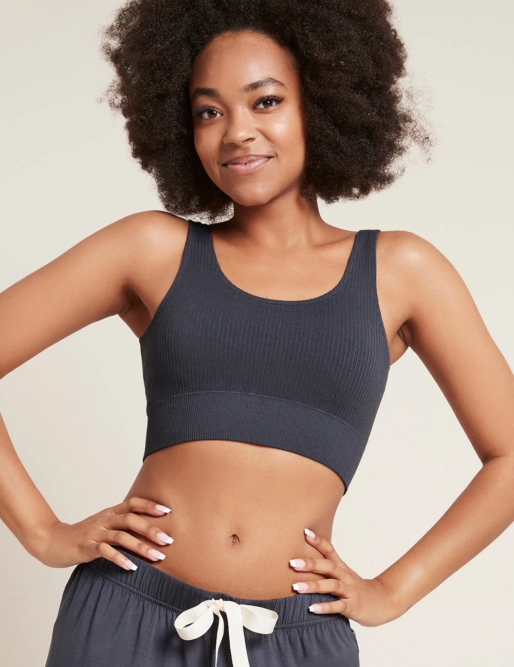 Woman wearing a dark blue sports bra and shorts on a beige background