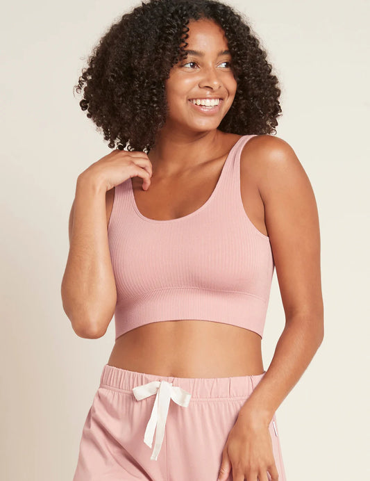 Woman wearing a pink crop top and pants against a beige background