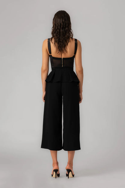 Person wearing a black jumpsuit with wide-leg pants on a gray background