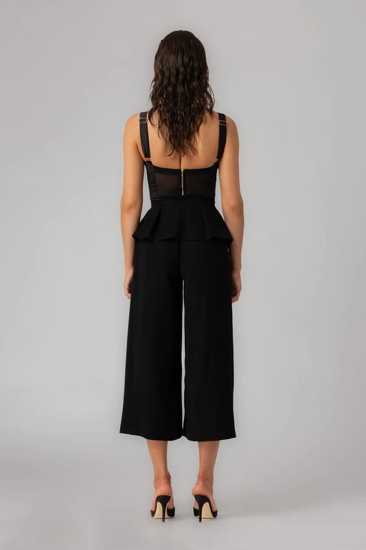 Person wearing a black jumpsuit with wide-leg pants on a gray background