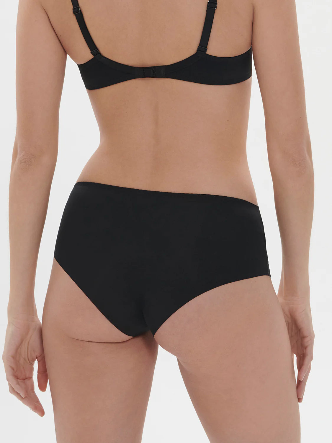 Person wearing a black bra and high-waisted underwear on a neutral background