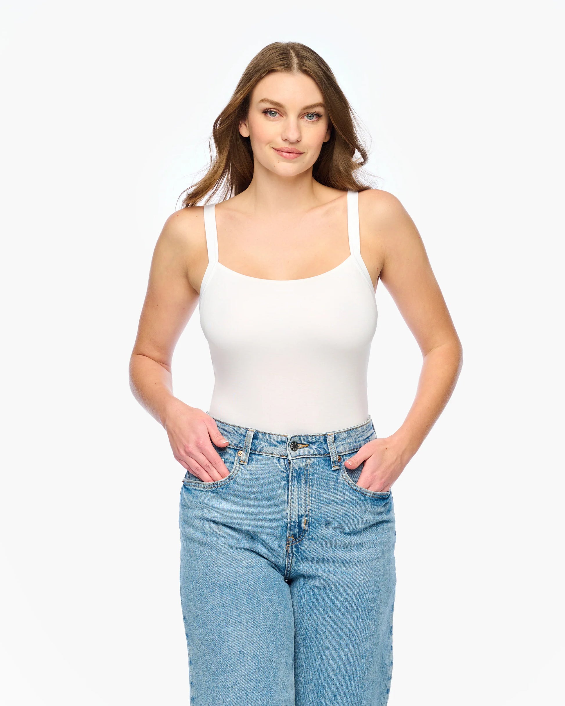 Woman wearing a white tank top and blue jeans on a white background