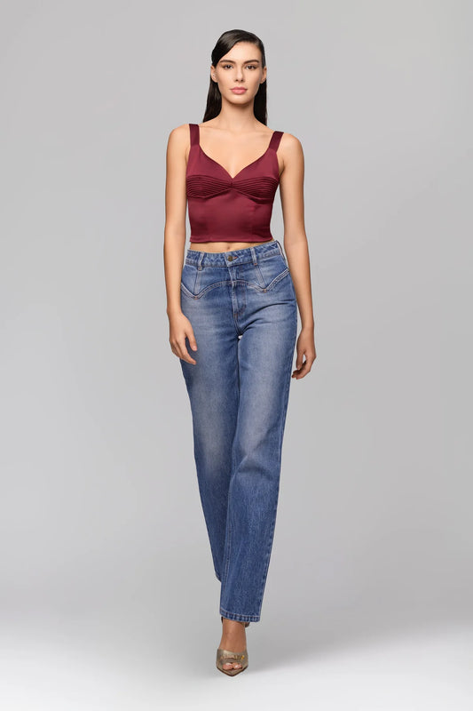 Woman wearing a burgundy top and blue jeans on a gray background