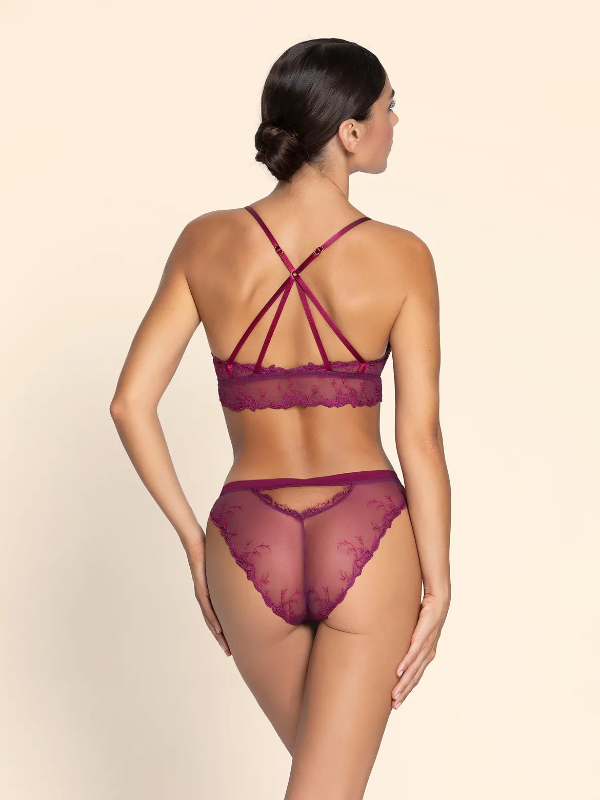 Woman wearing a burgundy lingerie set on a beige background