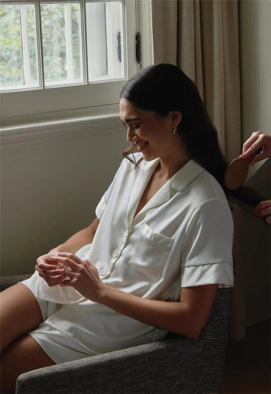 Woman in a white shirt sitting on a couch with a window in the background
