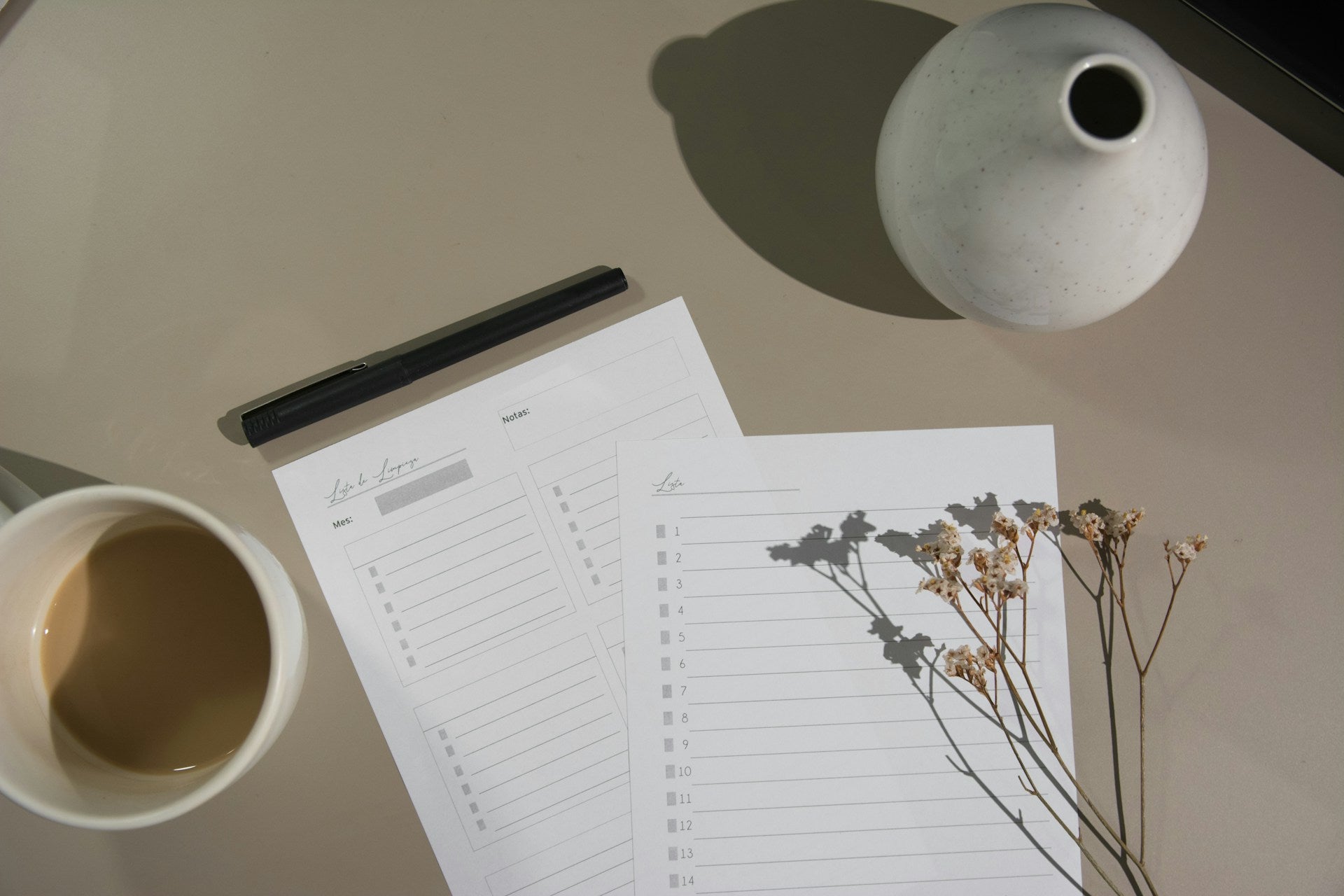 Desk with a coffee cup, pen, planner, and vase