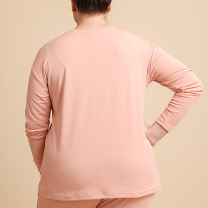 Person wearing a pink long-sleeve top and pants on a beige background