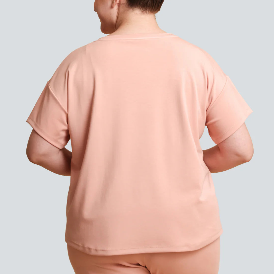 Person wearing a peach-colored outfit on a light gray background
