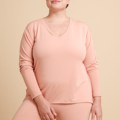 Person wearing a pink long-sleeve top and pants on a beige background