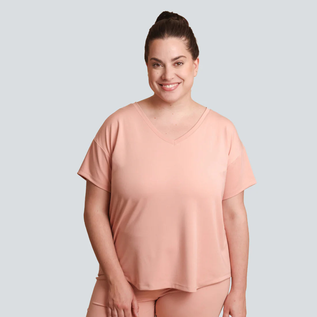 Woman wearing a peach-colored outfit on a light gray background