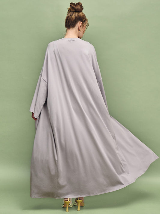 Woman wearing a long gray dress against a green background