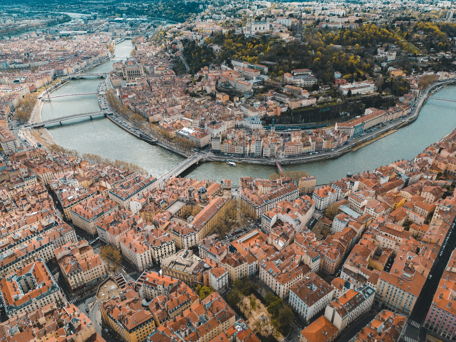 Aerial view of a city with red-roofed buildings and a river running through it.