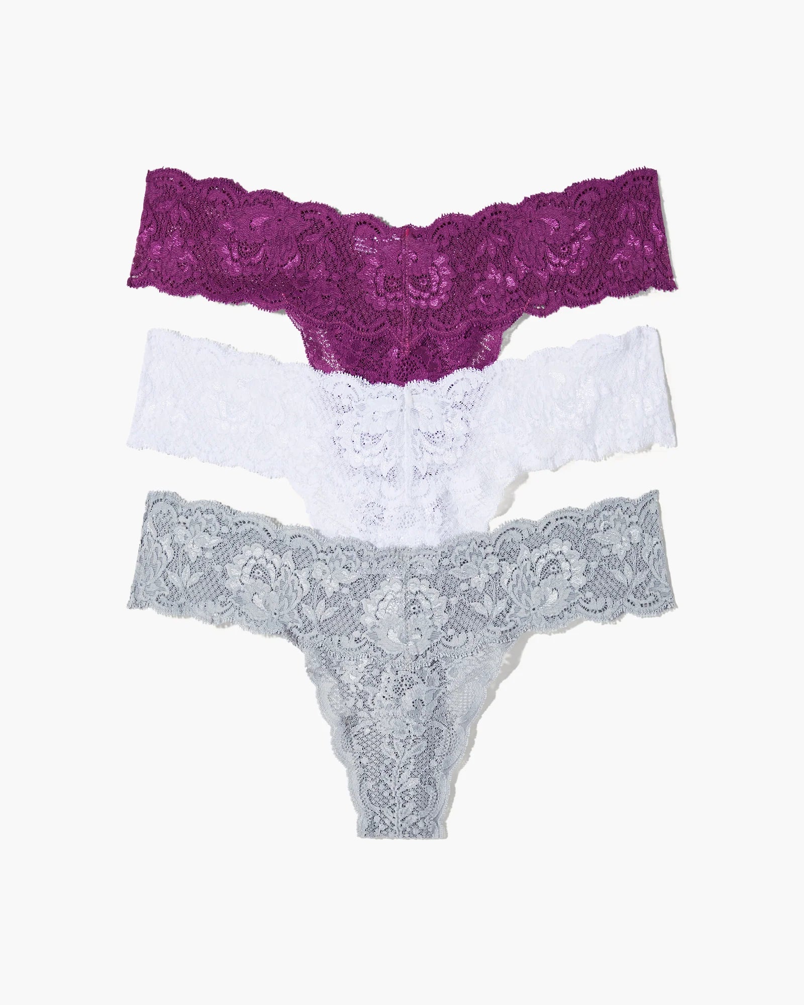 Set of three lace underwear pieces in purple, white, and gray on a white background