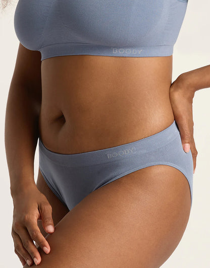 Person wearing a blue bra and underwear set on a neutral background