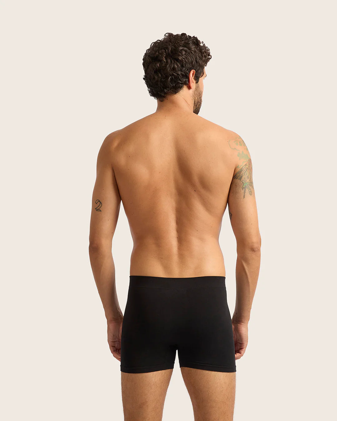 Man wearing black boxer briefs against a plain background