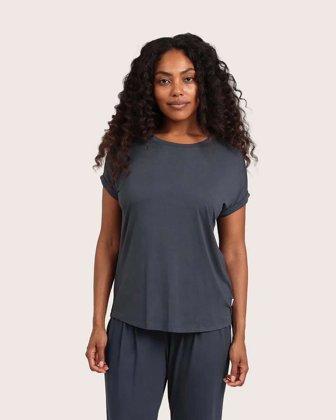 Woman wearing a dark gray t-shirt and pants on a beige background