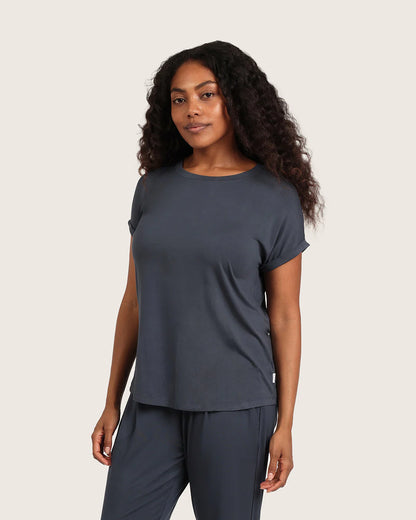 Woman wearing a dark gray t-shirt and pants on a beige background