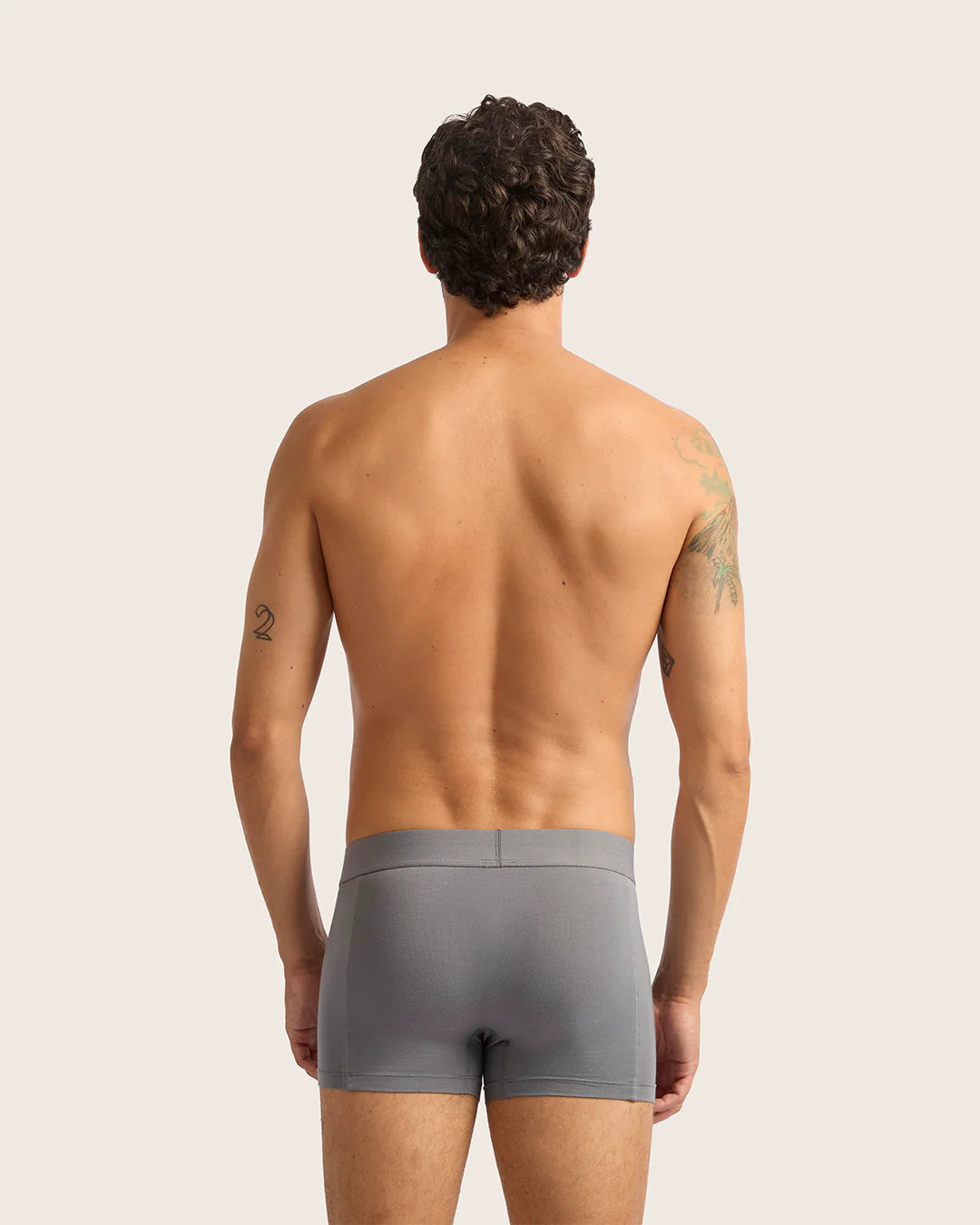 Man wearing gray boxer briefs against a plain background