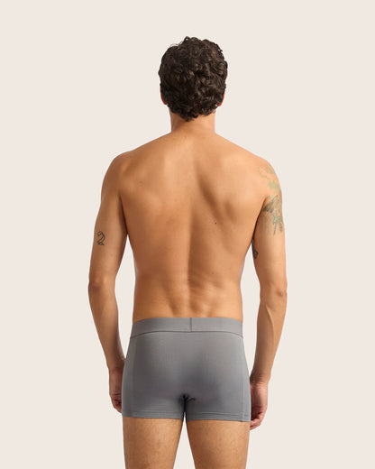 Man wearing gray boxer briefs against a plain background