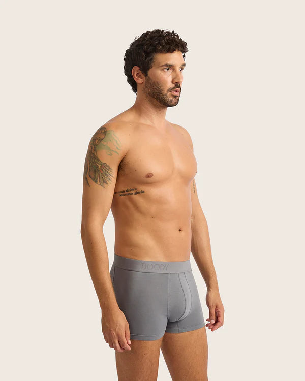 Man wearing gray boxer briefs against a plain background