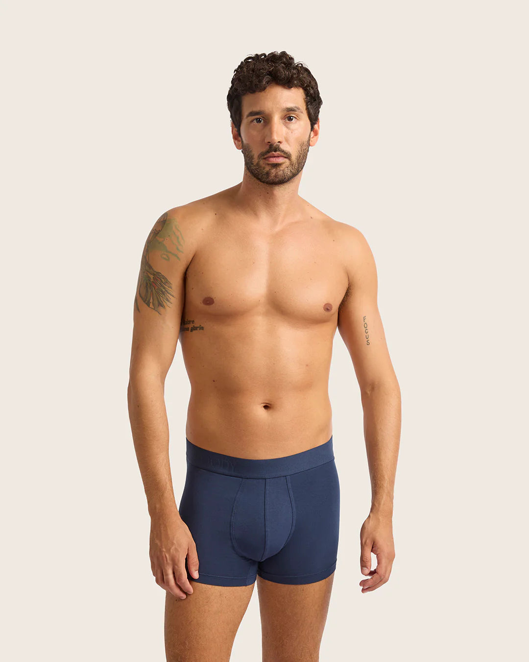 Man wearing navy blue boxer briefs against a plain background