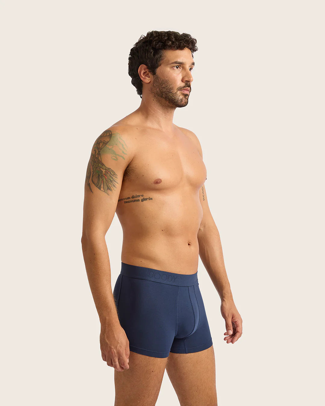 Man wearing navy blue boxer briefs against a plain background