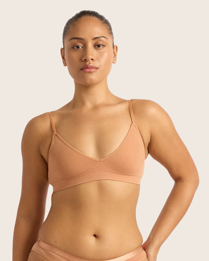 Woman wearing a beige sports bra and underwear set on a light pink background