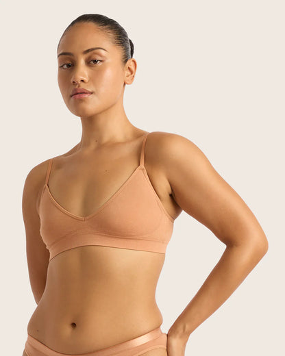 Woman wearing a beige tank top against a plain background