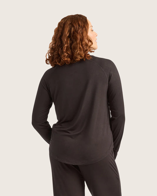 Person wearing a black long-sleeve top and pants on a light gray background