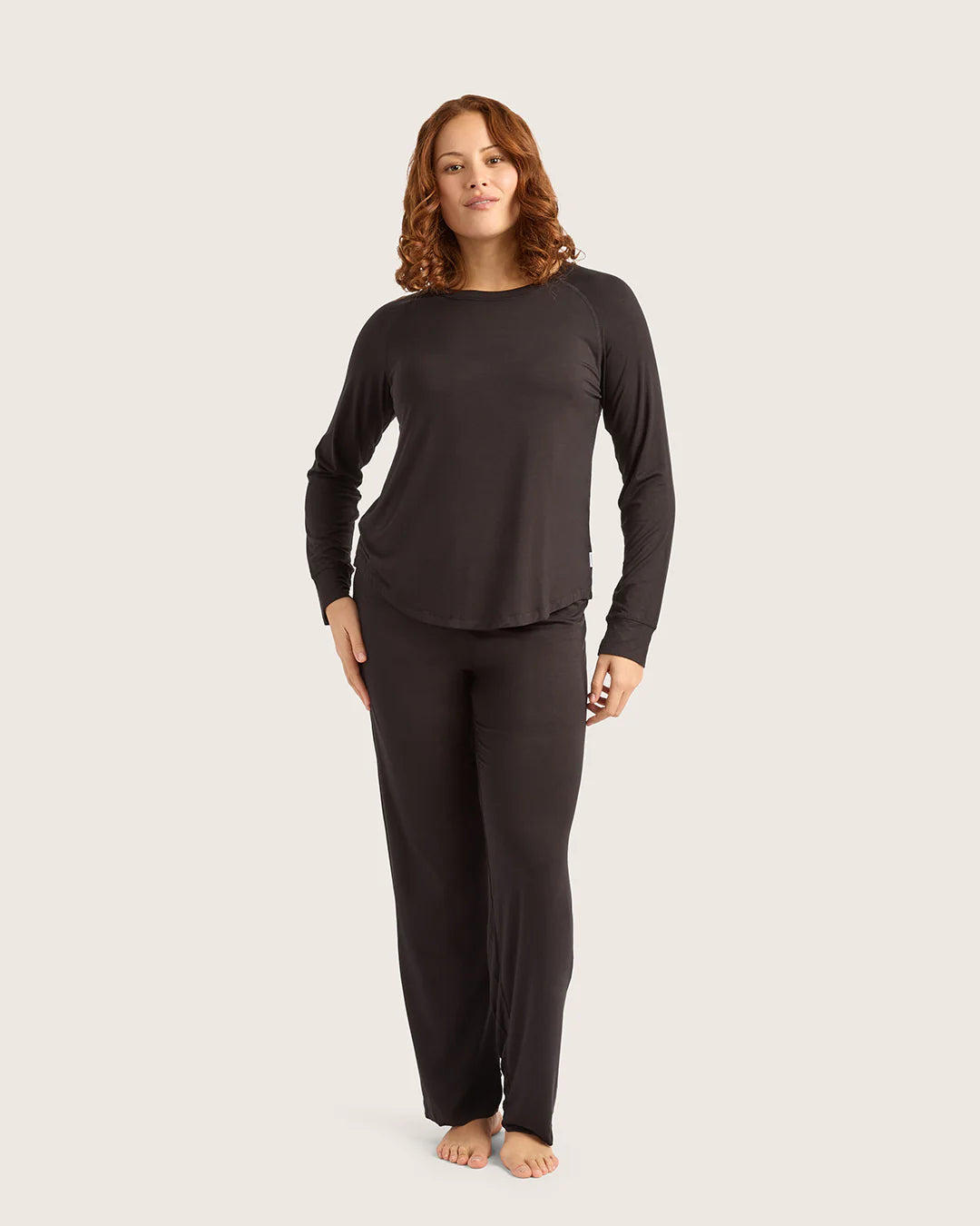 Woman wearing a black long-sleeve top and pants on a white background
