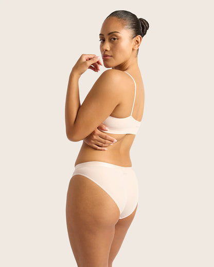 Woman wearing a beige bra and underwear set on a plain background