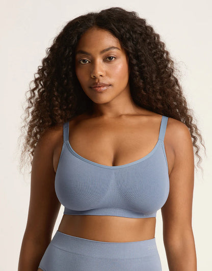 Woman wearing a blue sports bra and leggings against a neutral background
