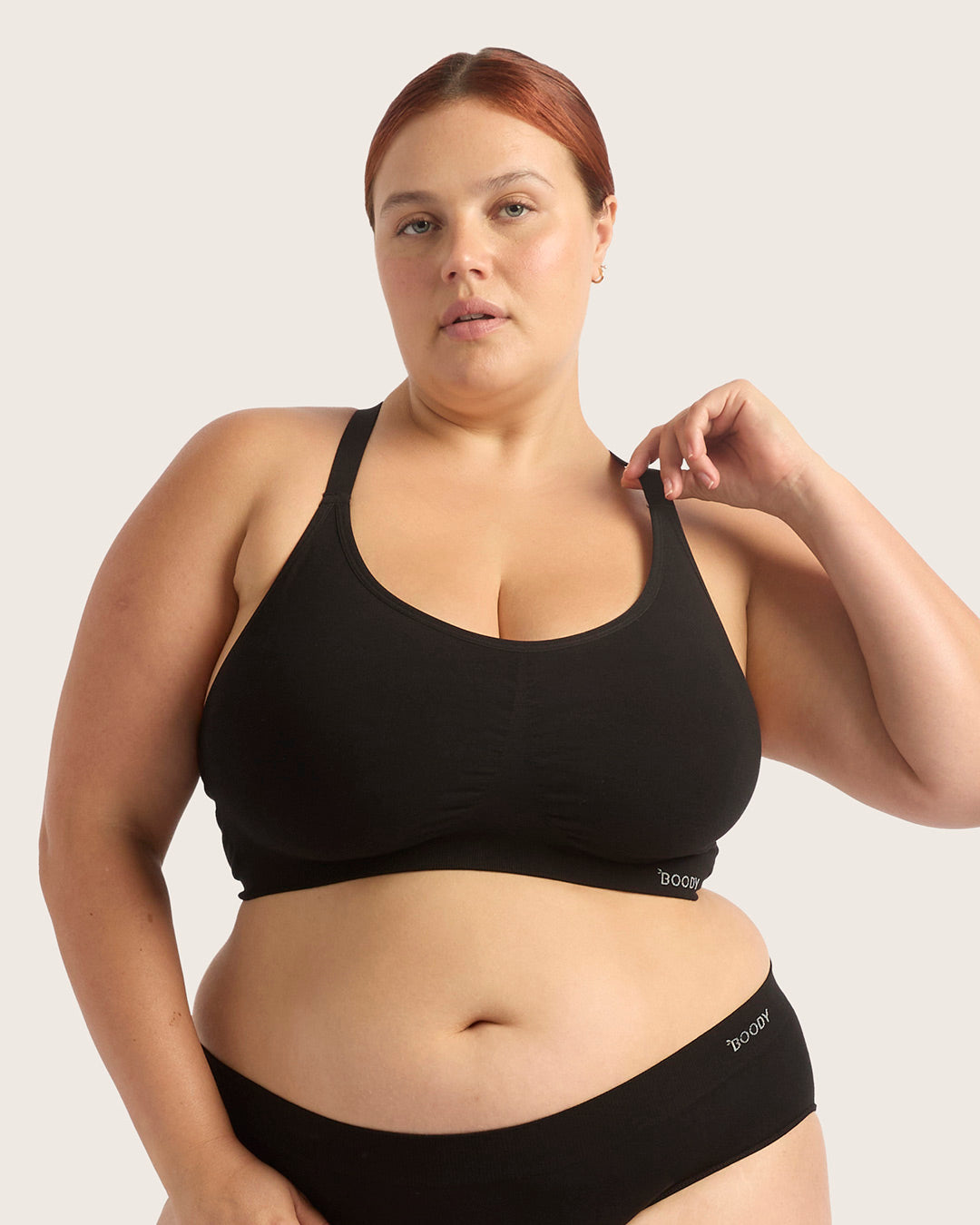 Woman wearing a black sports bra and underwear set on a light gray background