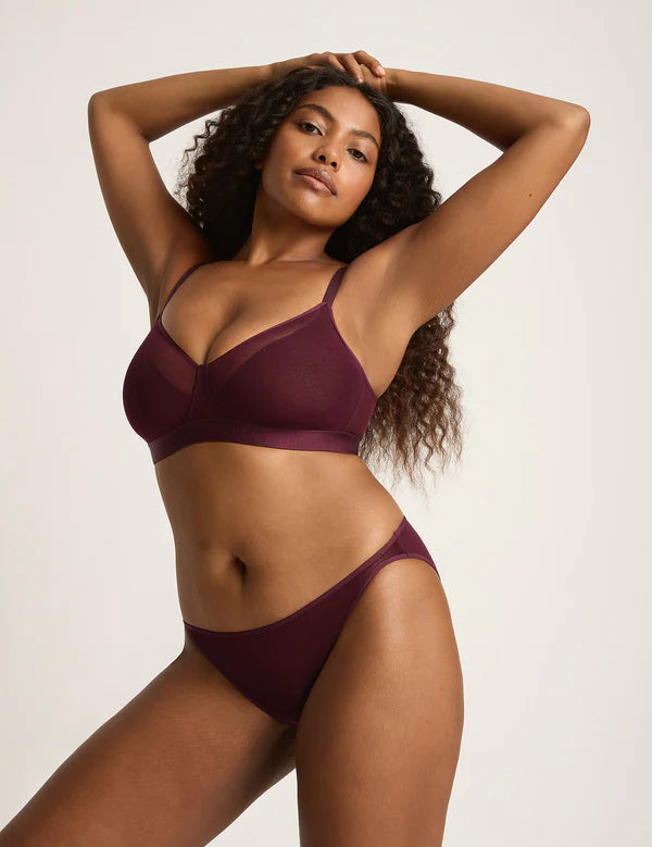 Woman wearing a burgundy lingerie set against a plain background