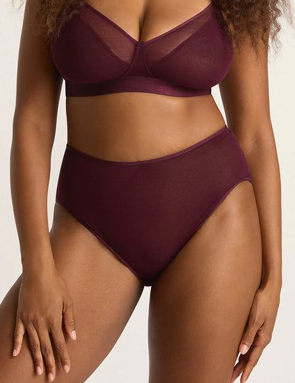 Person wearing a burgundy bra and panties set on a neutral background