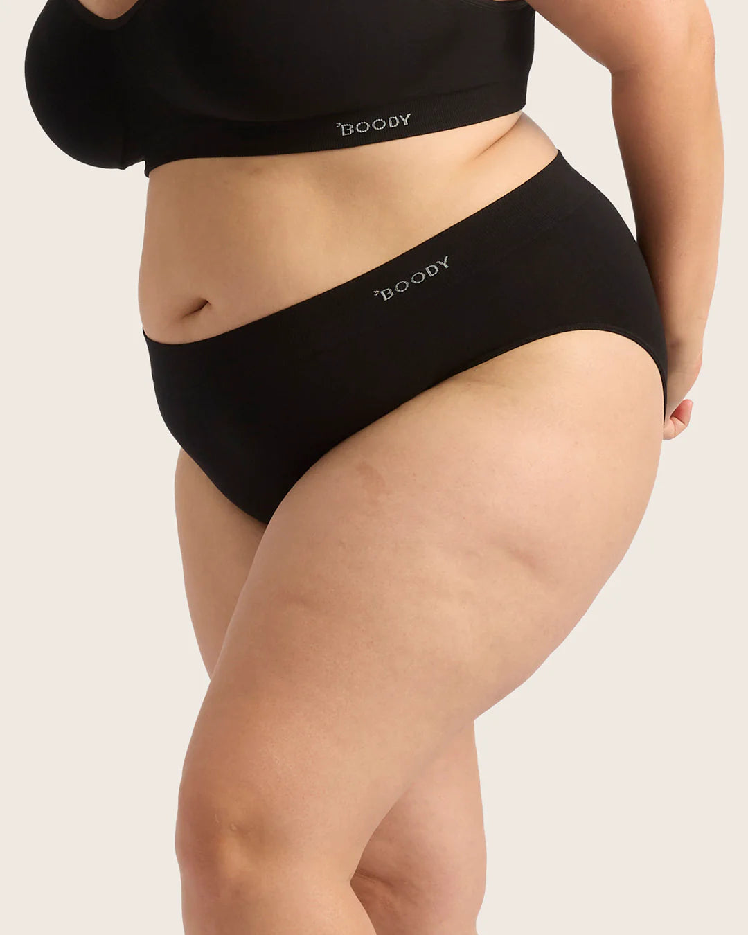 Person wearing black Boody underwear on a beige background