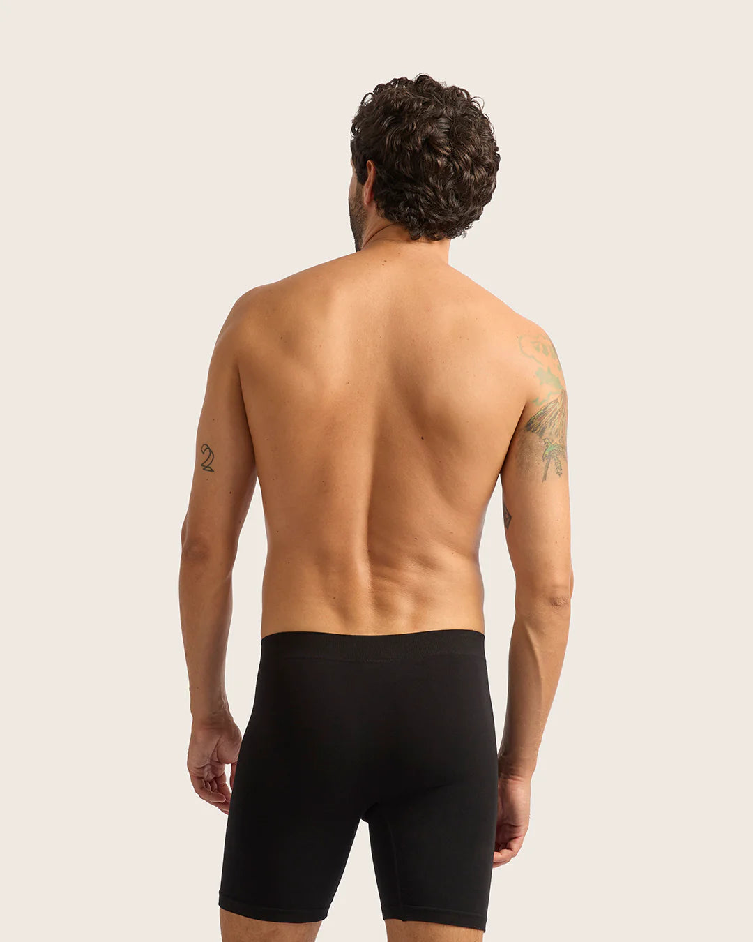 Man wearing black underwear against a plain background