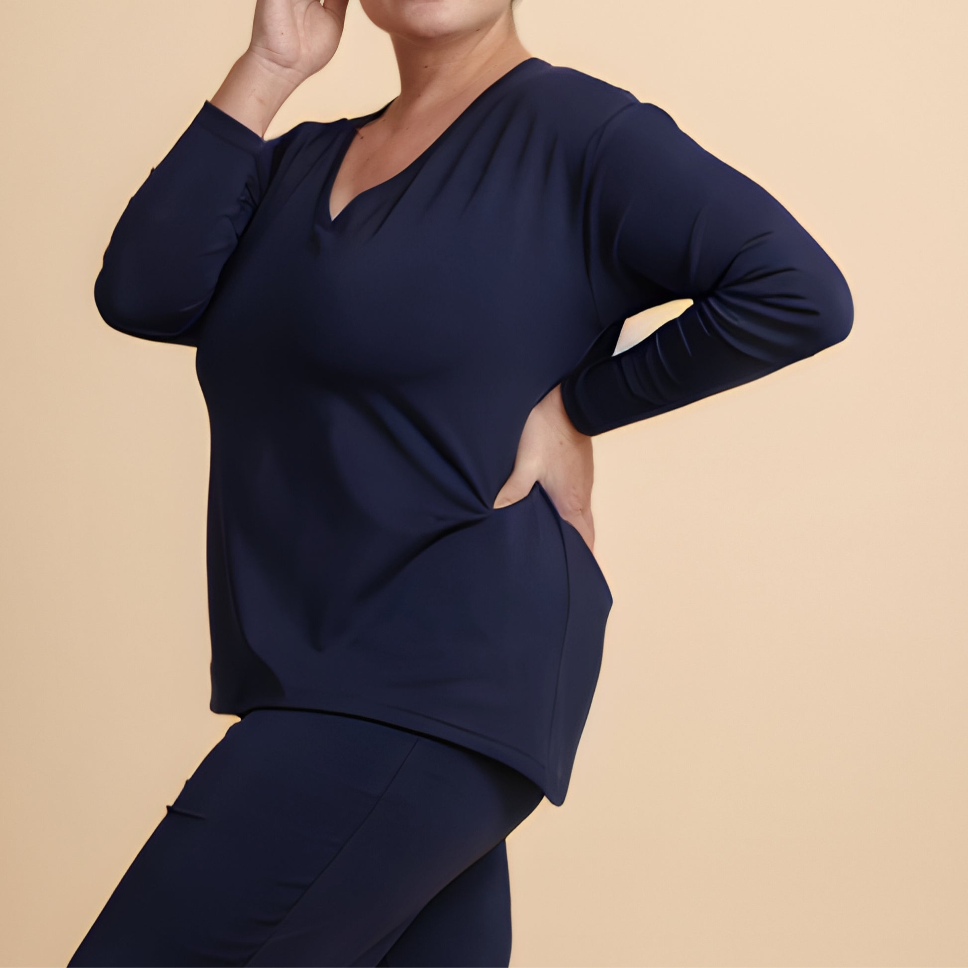 Navy blue long-sleeve top with cutout design on a beige background