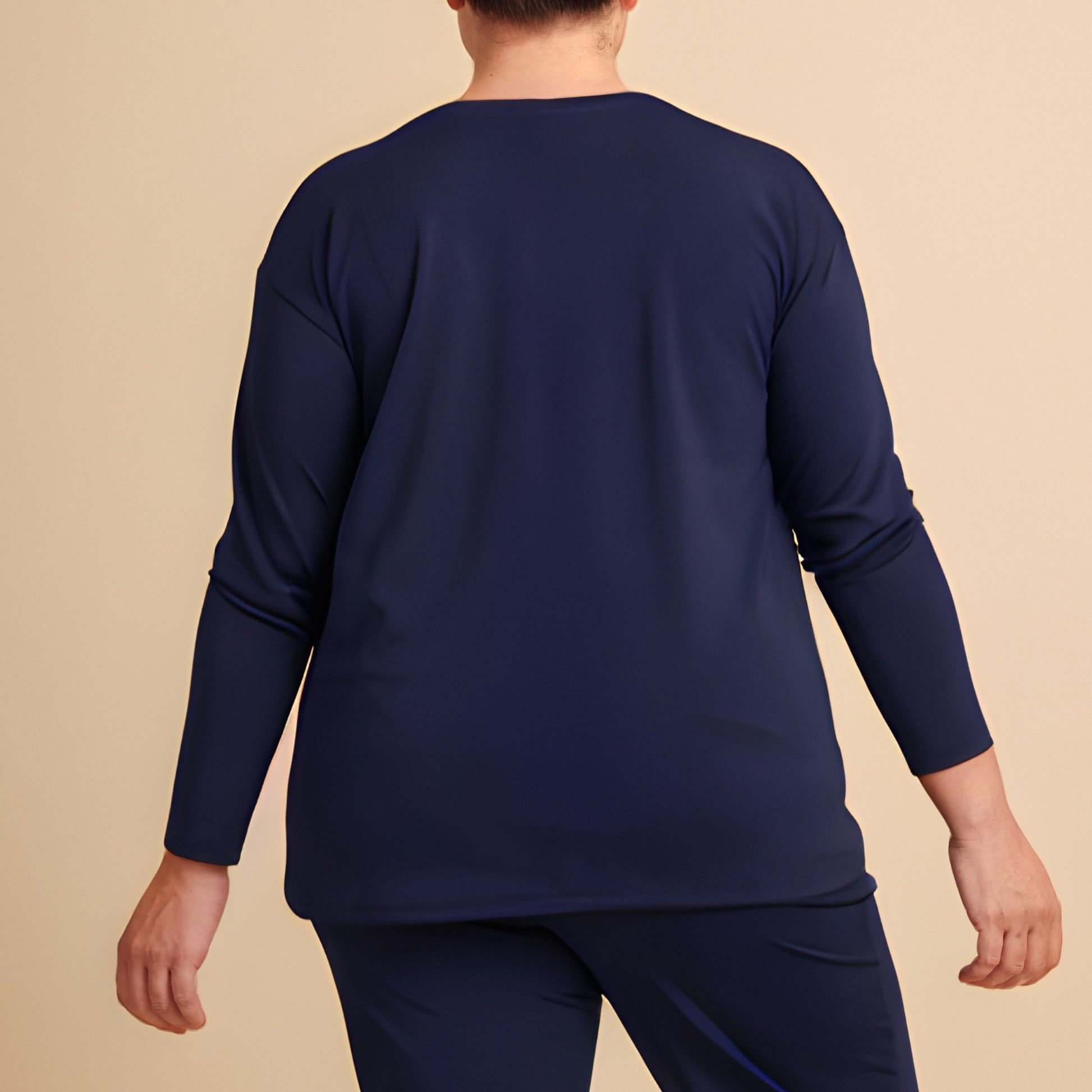 Person wearing a navy blue long-sleeve shirt and pants on a beige background