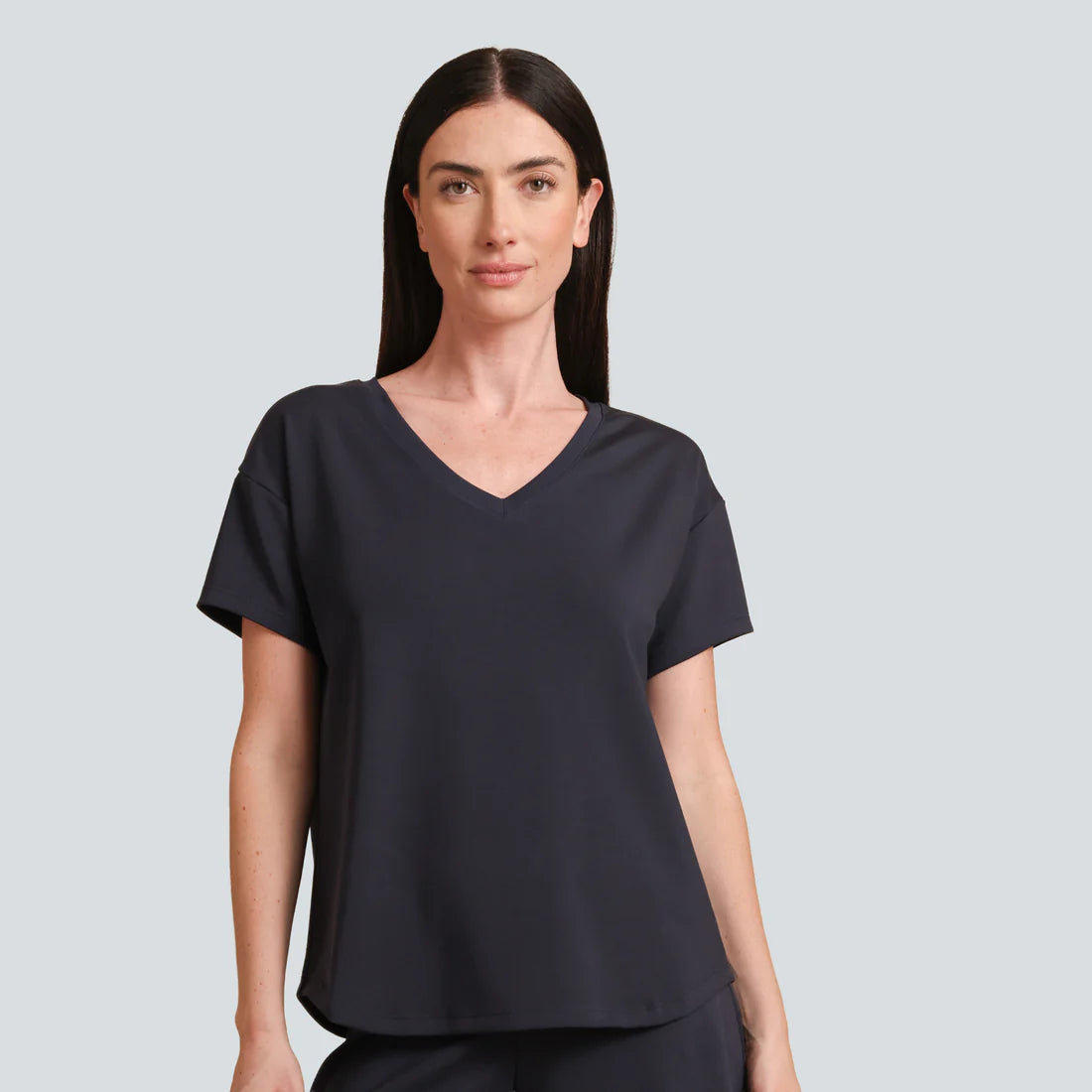 Woman wearing a black V-neck t-shirt against a light gray background