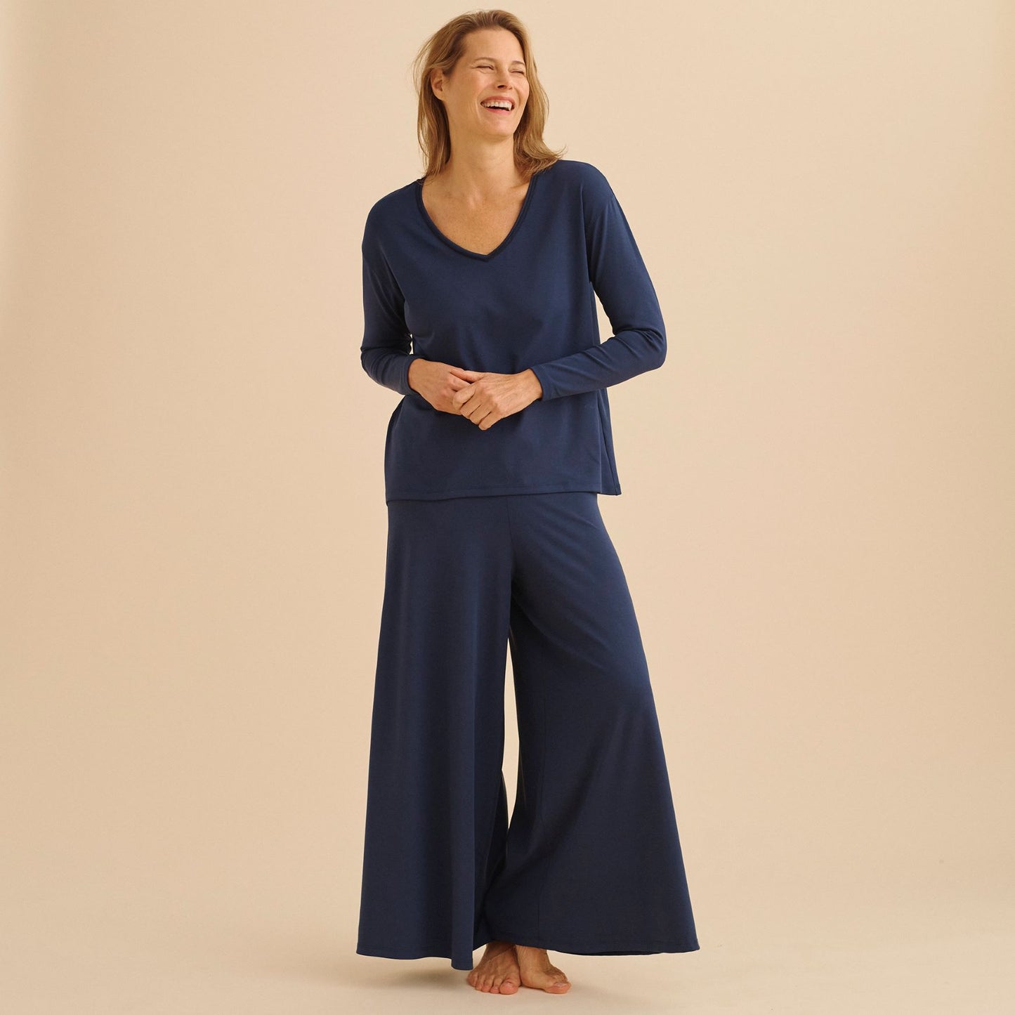 Woman wearing a navy blue pajama set on a beige background