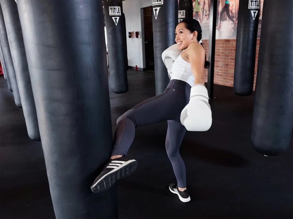 Woman in a gym setting with punching bags, wearing athletic gear.