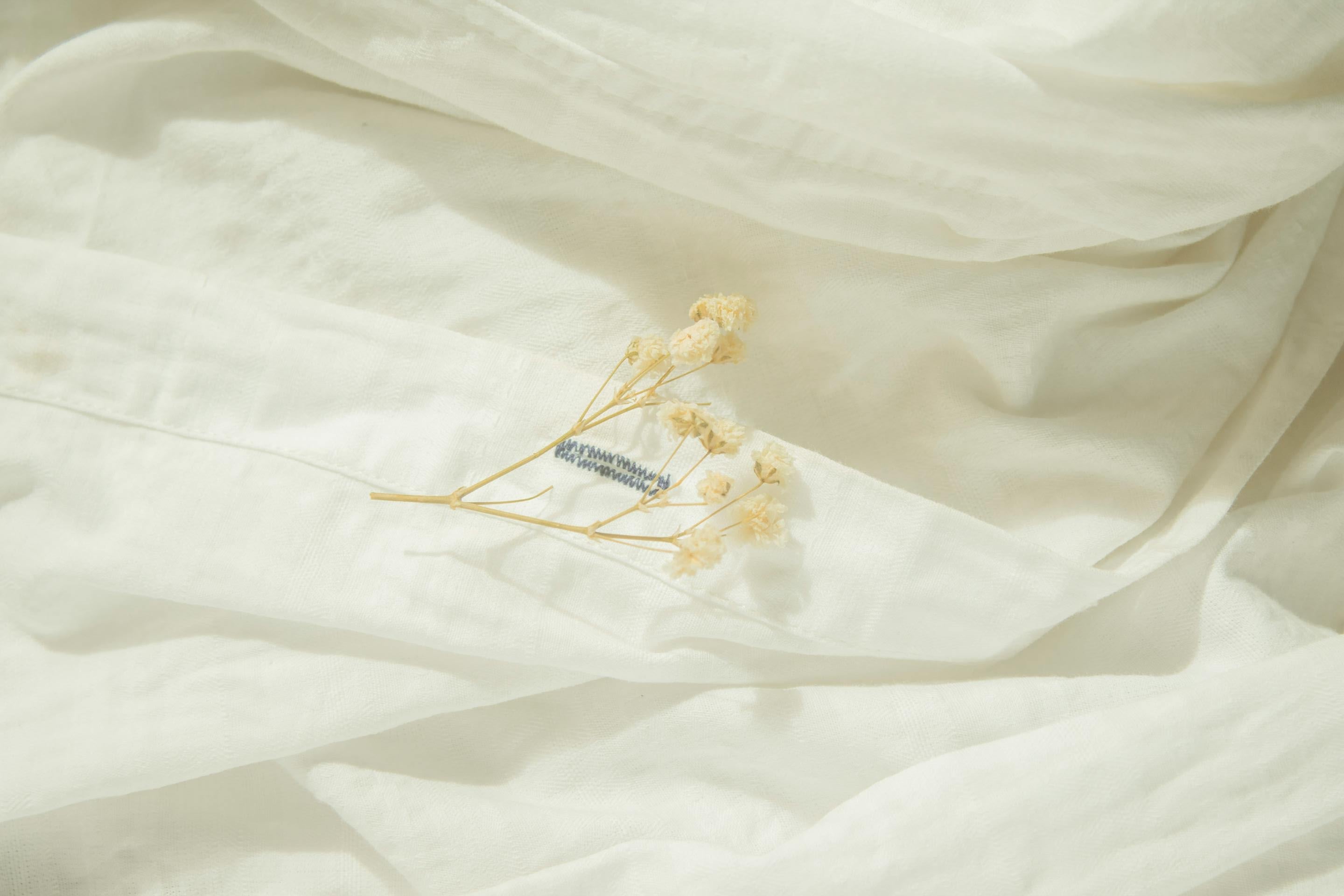 White fabric with a small dried flower and label on a light background