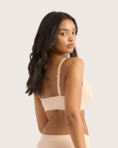 Woman wearing a beige bra and underwear set against a plain background
