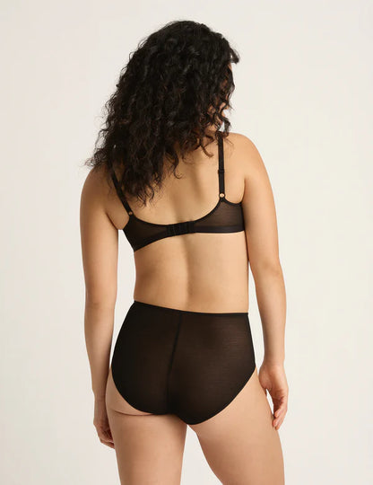 Woman wearing a black bra and panties set on a beige background