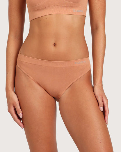 Person wearing a peach-colored sports bra and leggings set on a light gray background