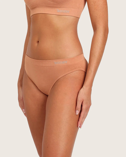 Person wearing a peach-colored bikini set on a light beige background