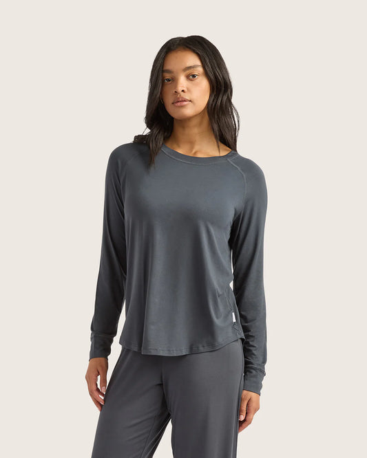 Woman wearing a gray long-sleeve top and pants on a light background